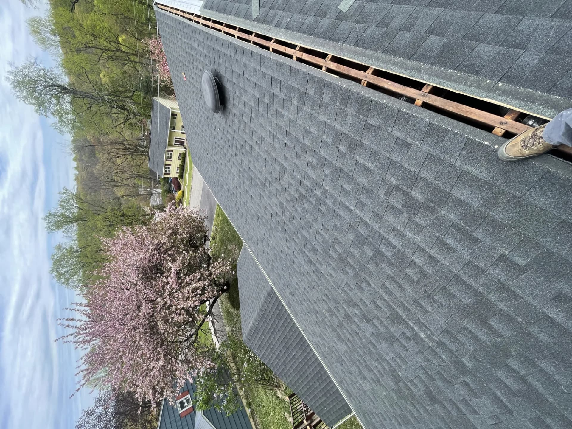 Charcoal asphalt shingle ridge cap being installed on a residential roof in New Jersey