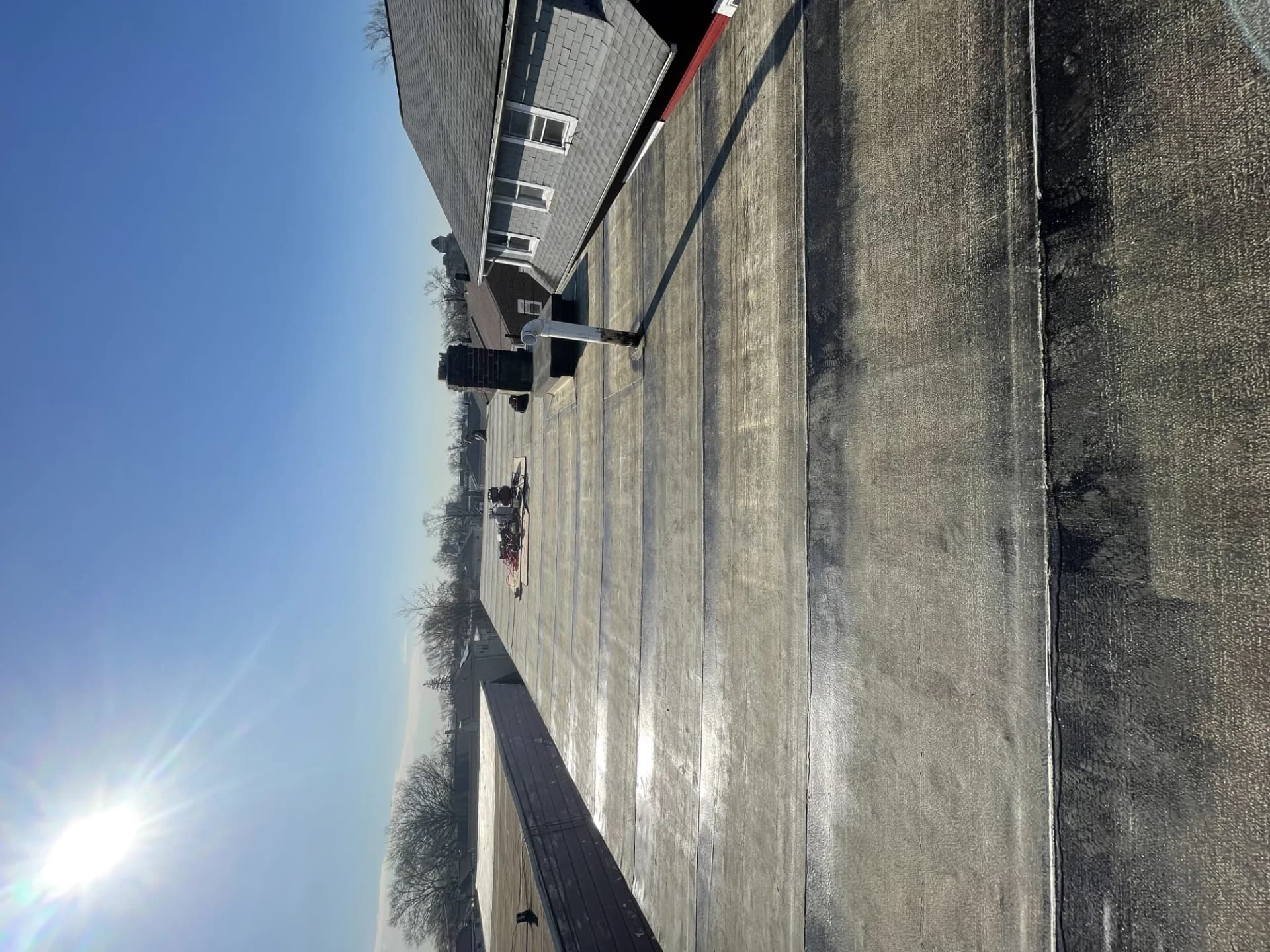 Wide aerial view of a large commercial flat roof with a black membrane surface on a clear day in New Jersey