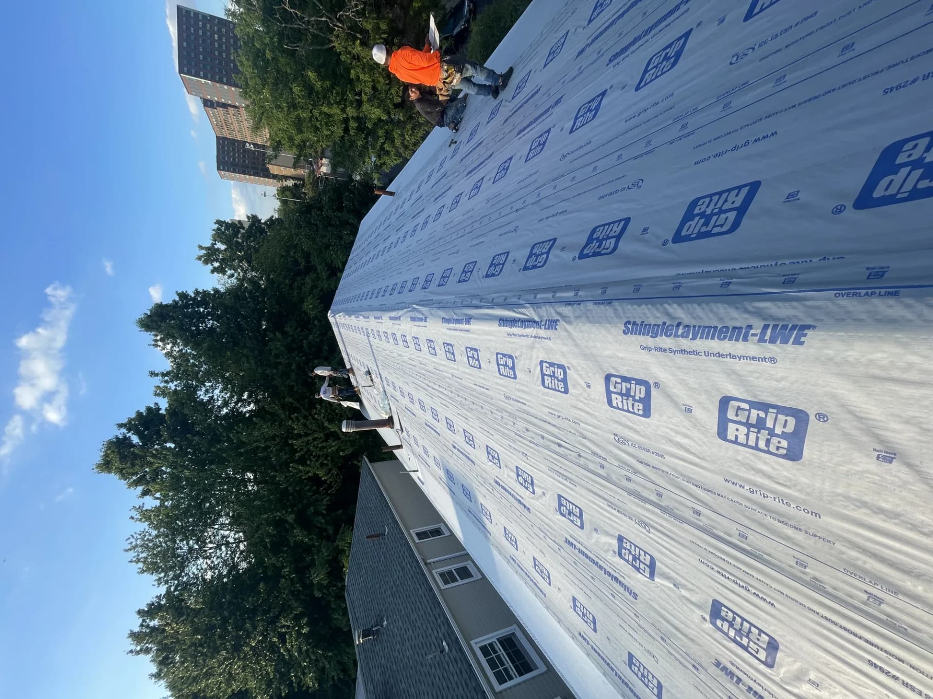 Crew rolling out Grip-Rite ShingleLayment synthetic underlayment on a large residential roof slope in New Jersey