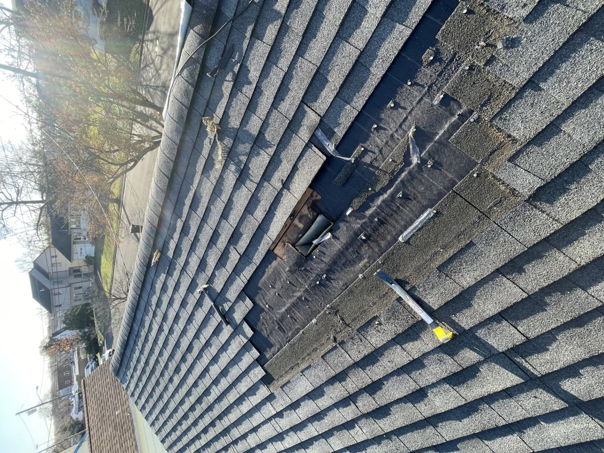 Aging asphalt shingle roof with missing shingles and an open hole on a New Jersey home