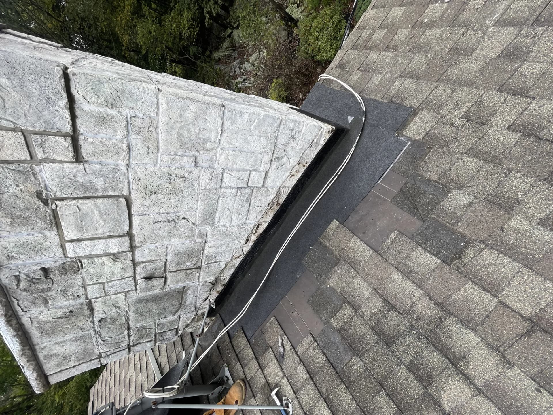Natural stone chimney beside an asphalt shingle roof on a New Jersey home by Alpha Pro Construction