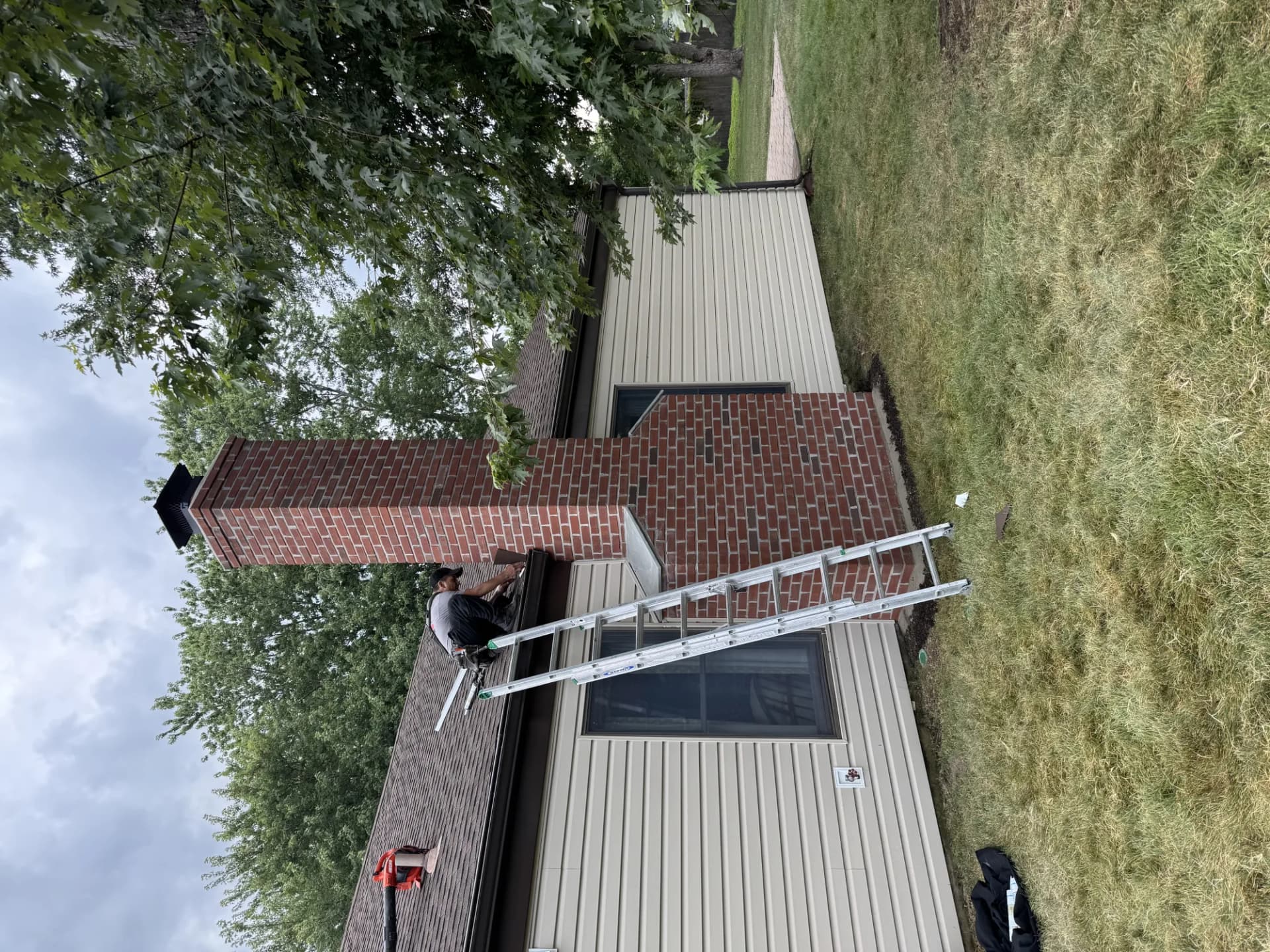 Tall brick chimney beside a metal roof repair on a New Jersey building