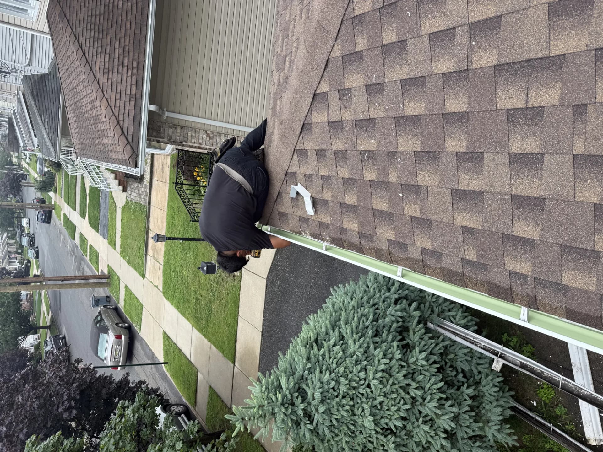 Technician installing a white seamless aluminum gutter along the eave of a New Jersey home