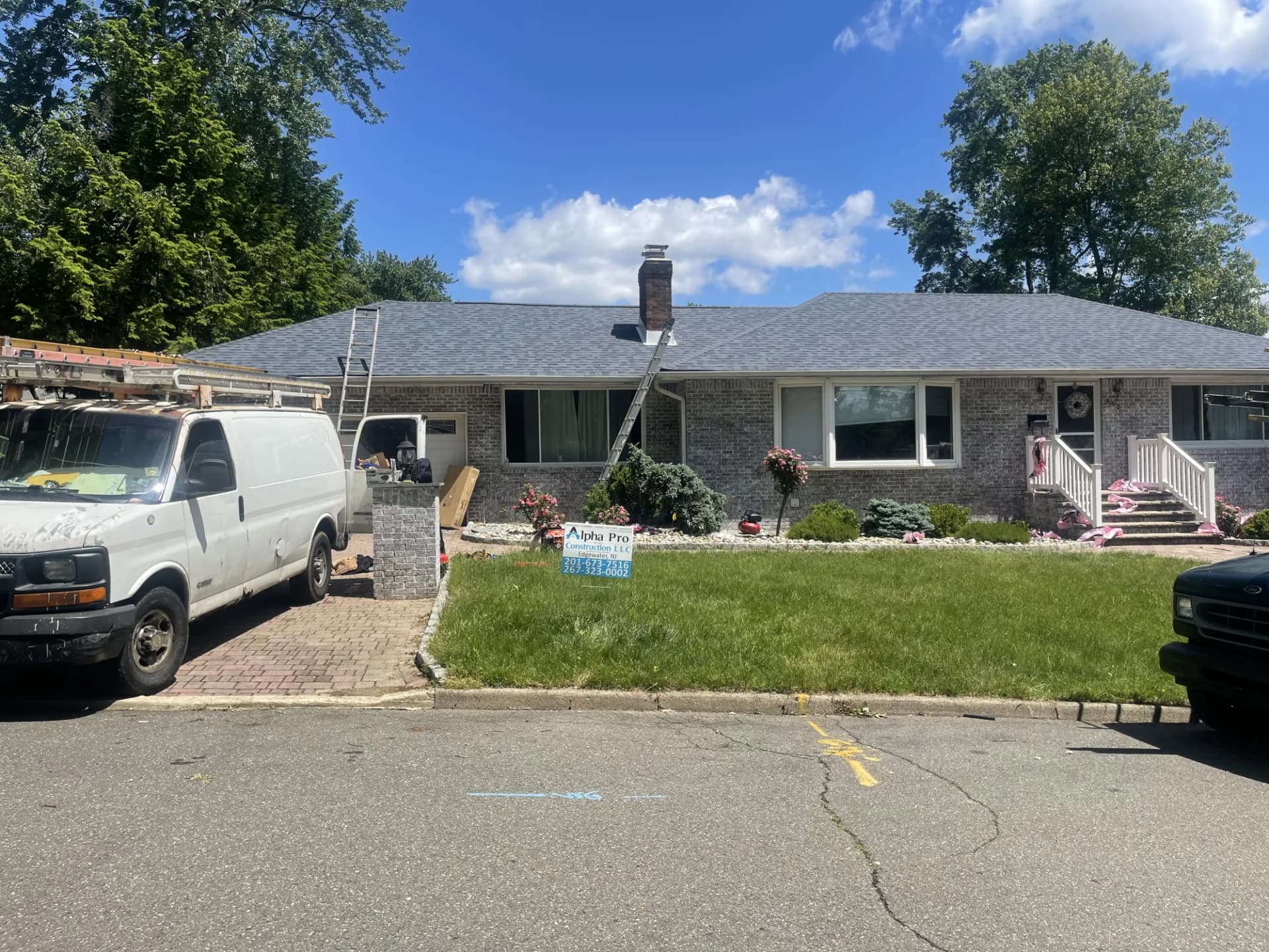 Alpha Pro Construction crew replacing the roof on a brick ranch home with new dark shingles in New Jersey