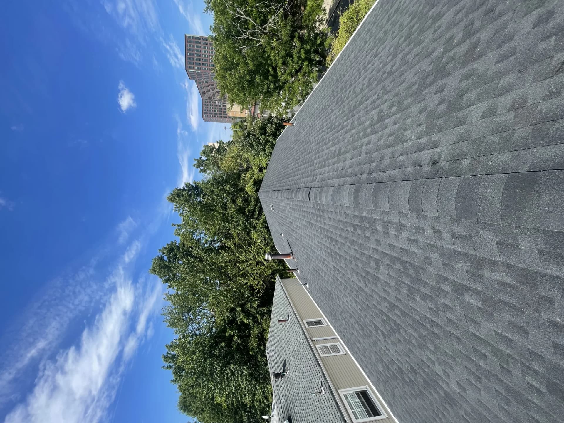 Steep charcoal asphalt shingle gable roof with ridge cap on a New Jersey home before winter