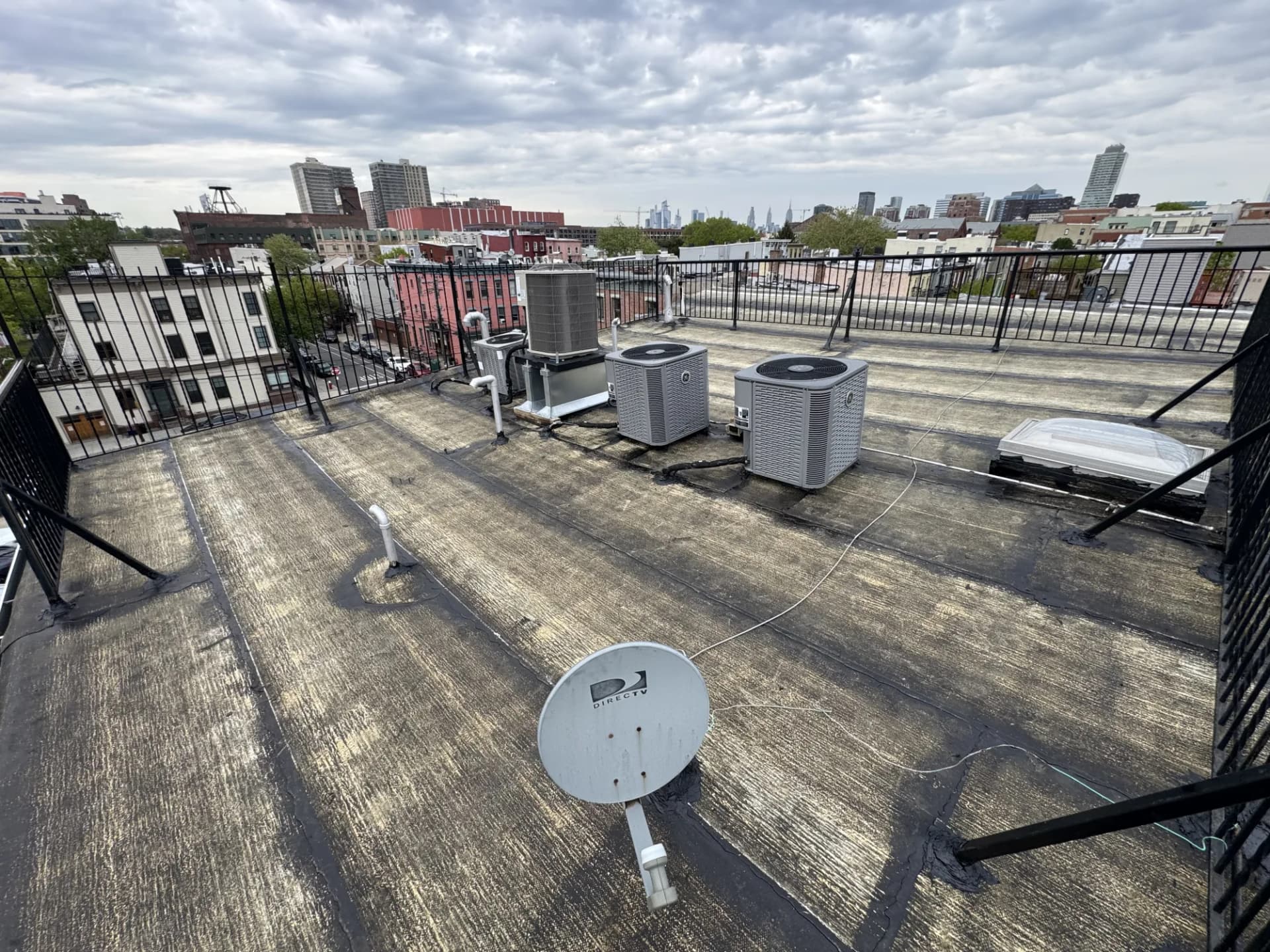 Inspector examining a commercial flat roof membrane and rooftop HVAC units on a New Jersey building