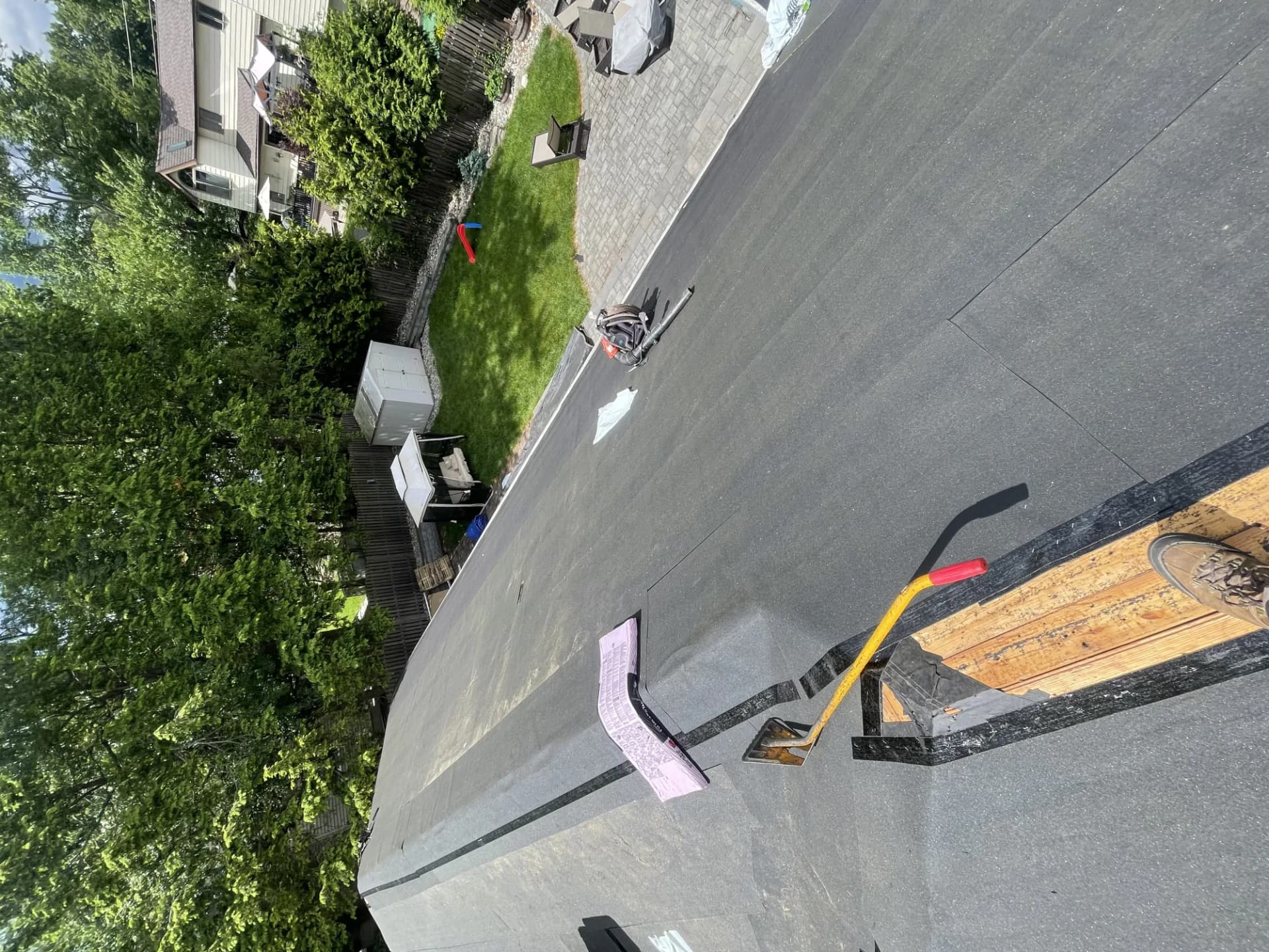 Flat rubber membrane roof being installed on a residential property in New Jersey with tools on the deck