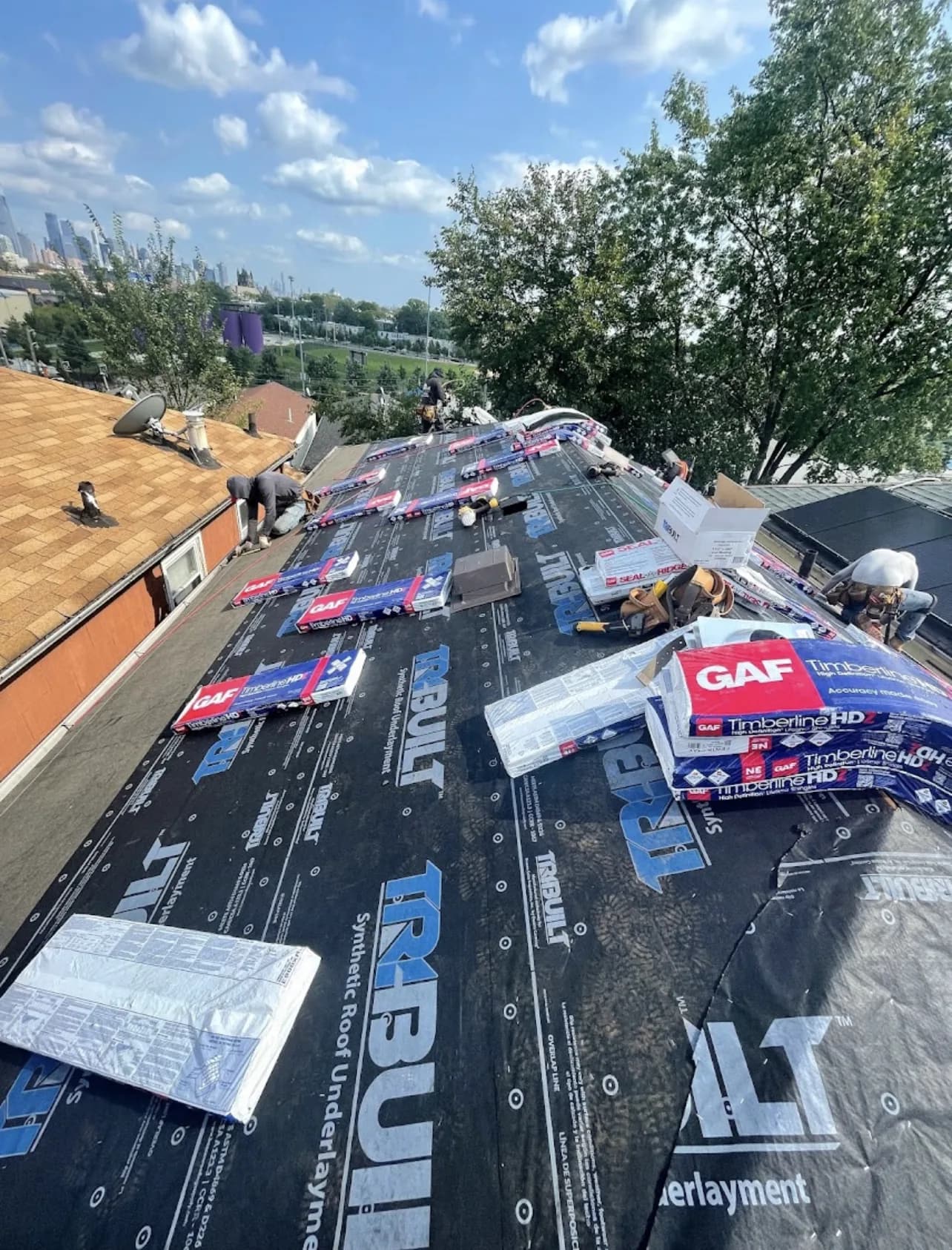 Roofing crew installing GAF Timberline HD shingles over TriBuilt synthetic underlayment on a roof in New Jersey