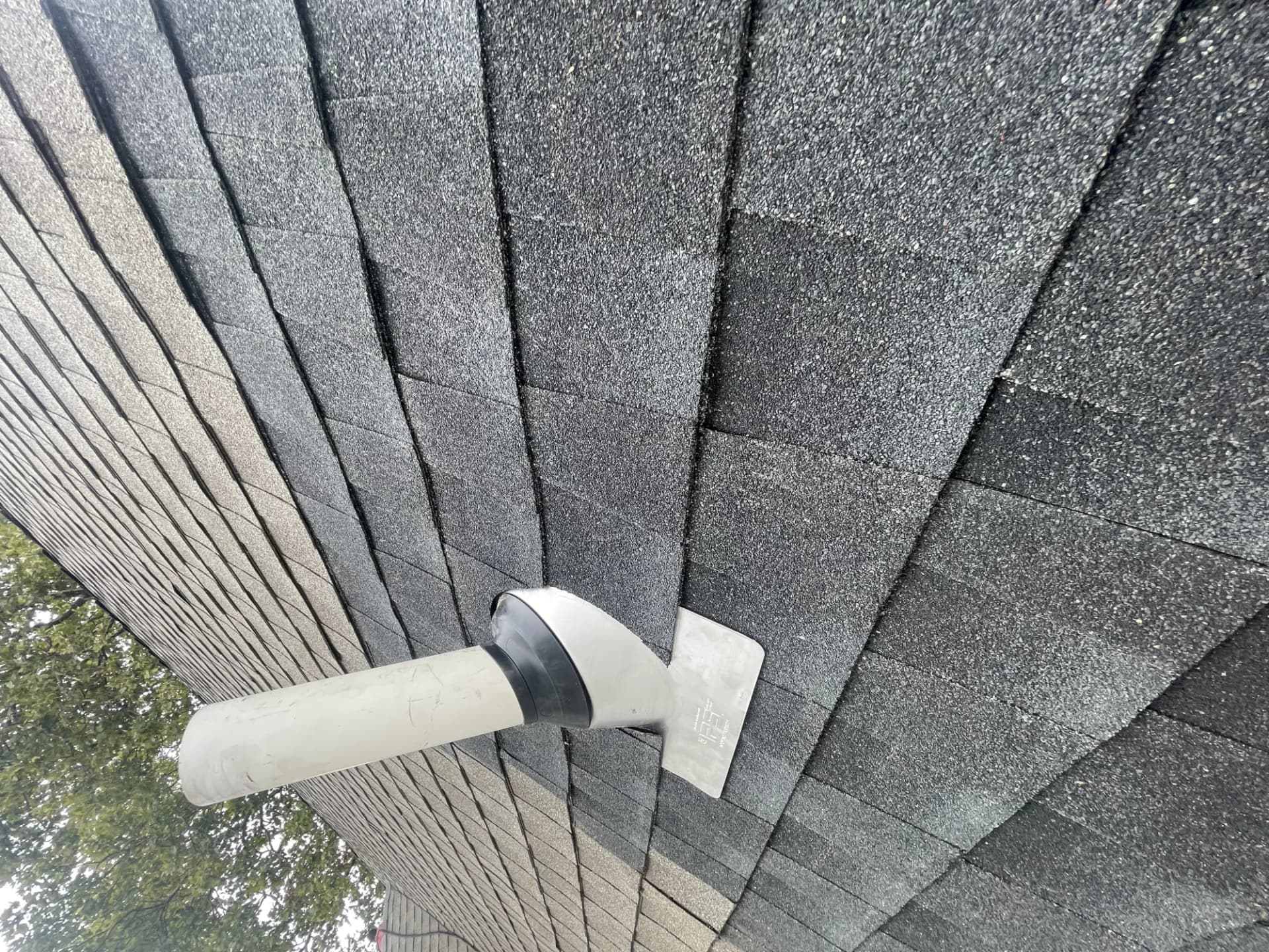 Plumbing vent pipe boot with a rubber collar on a charcoal architectural shingle roof in New Jersey