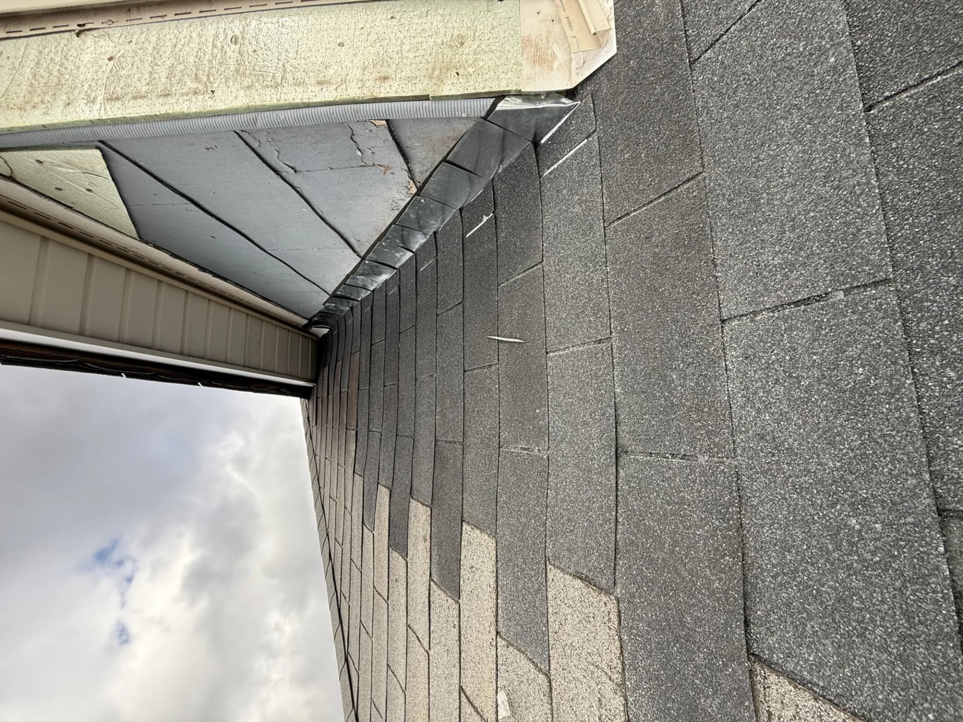 Storm-damaged shingle eave and torn flashing on a residential roof in New Jersey requiring insurance repair