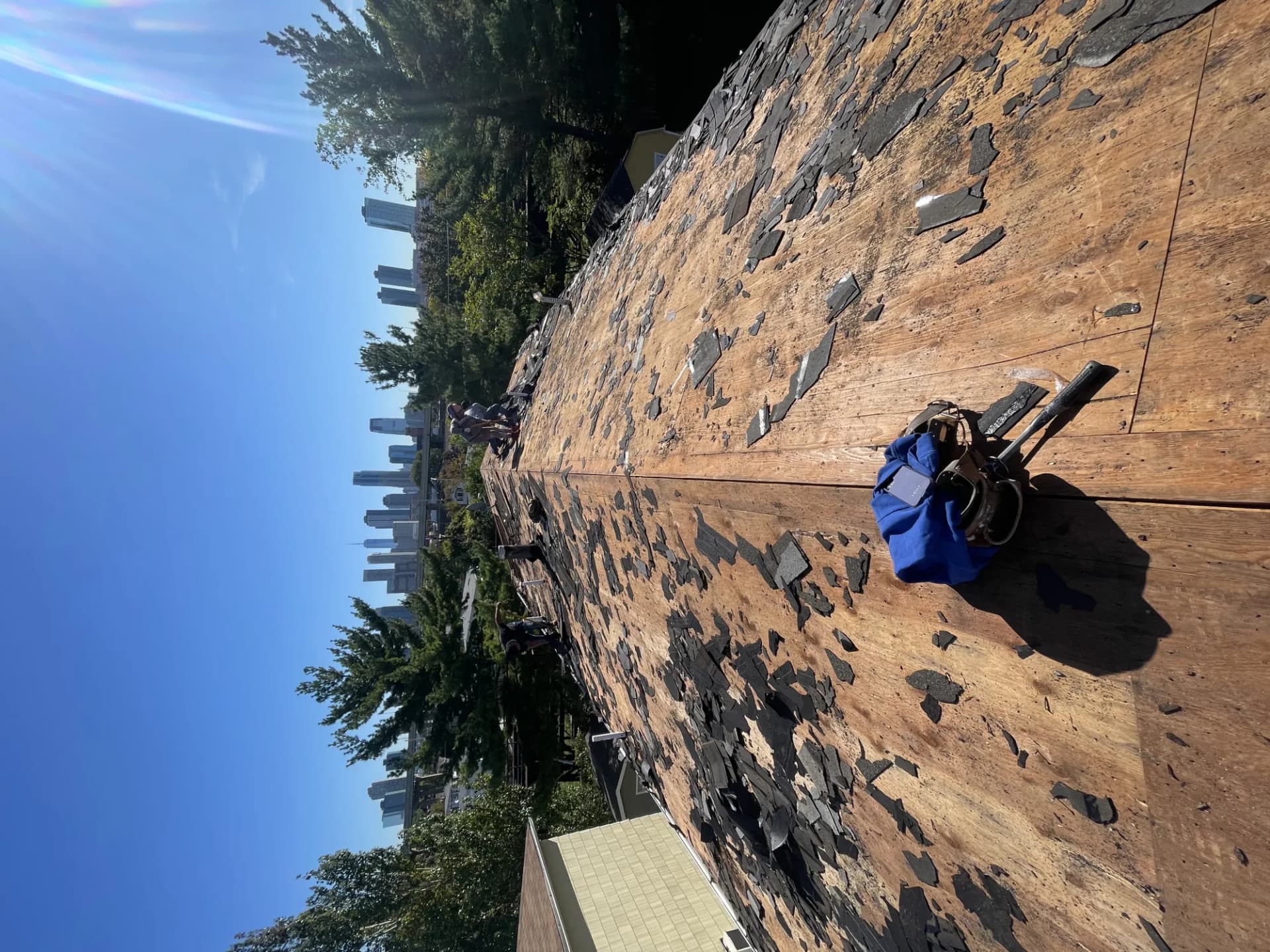Storm-torn asphalt shingles on a stripped residential roof deck in New Jersey after a windstorm